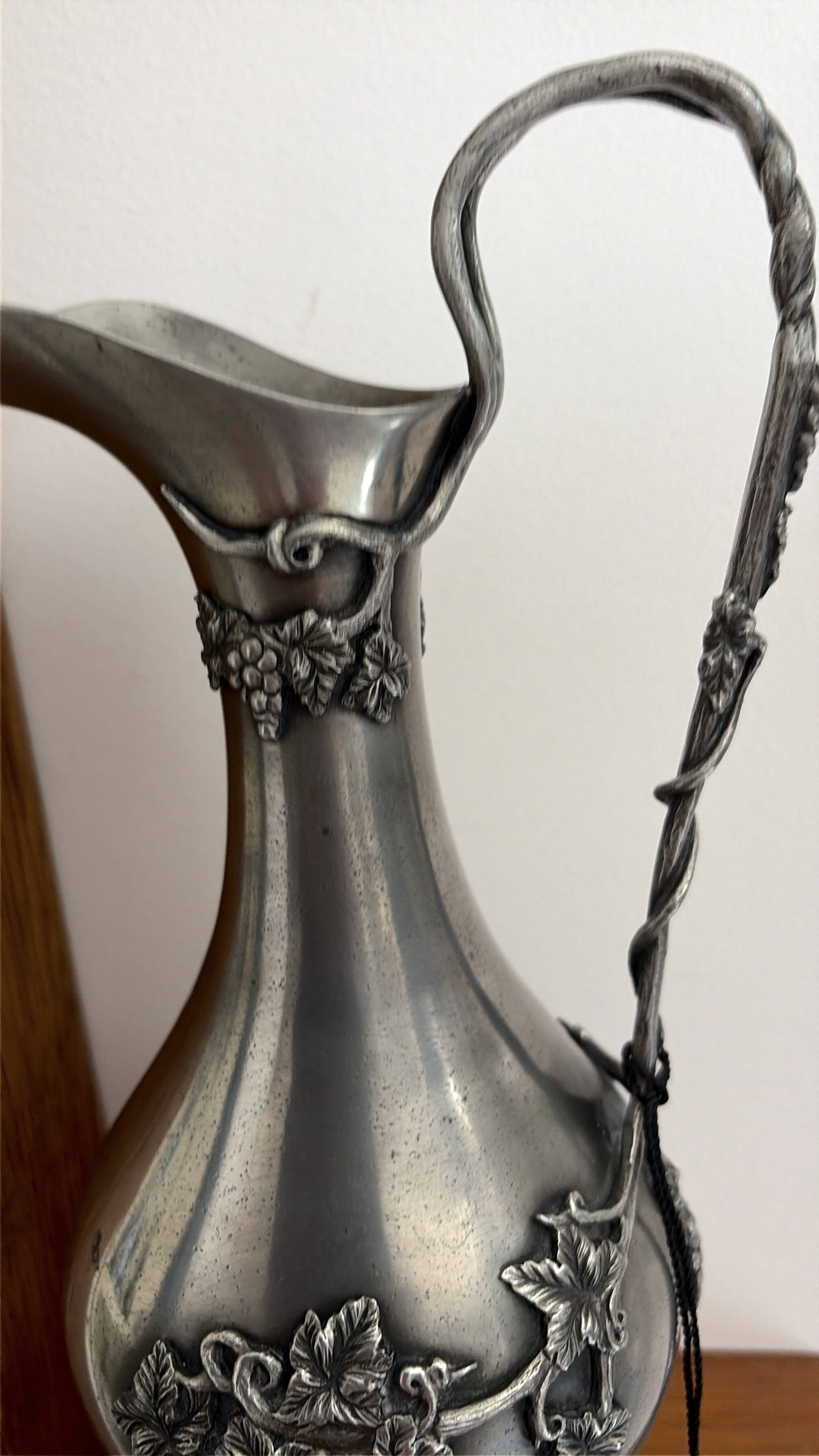 Ewer in pewter surrounded by vine branches with g