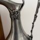 Ewer in pewter surrounded by vine branches with g