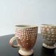 Set of 2 enamelled stoneware mugs with stylised polka dots.