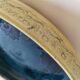Blue floral glazed stoneware plate with a yellow rim.