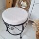 Black iron stool/pouf with its boucle fabric cushion.