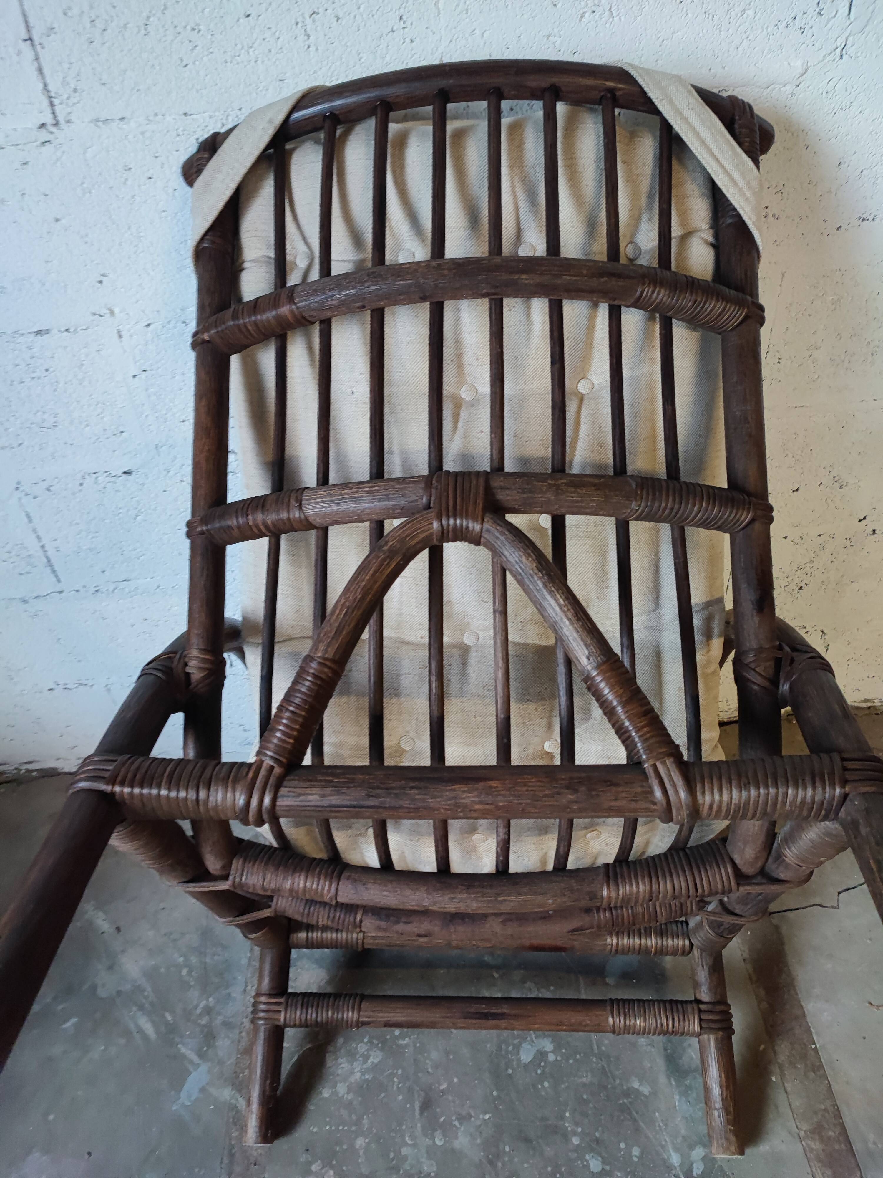 Relaxed armchair in bamboo and rattan with its small side table. Beige linen cushion.