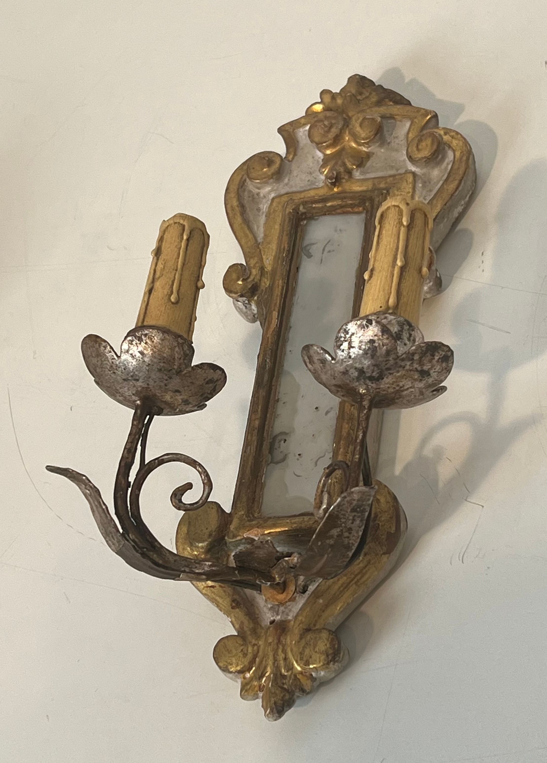 Pair of wall sconces in carved wood and silvered and gilded patinated metal with a central mirror.