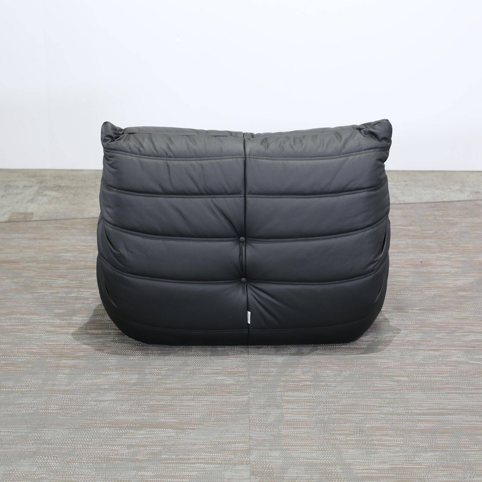Togo armchair and footrest in black leather by Ligne Roset, designed by Michel Ducaroy.