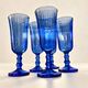 Set of 5 blue glass champagne flutes with faceted stems.