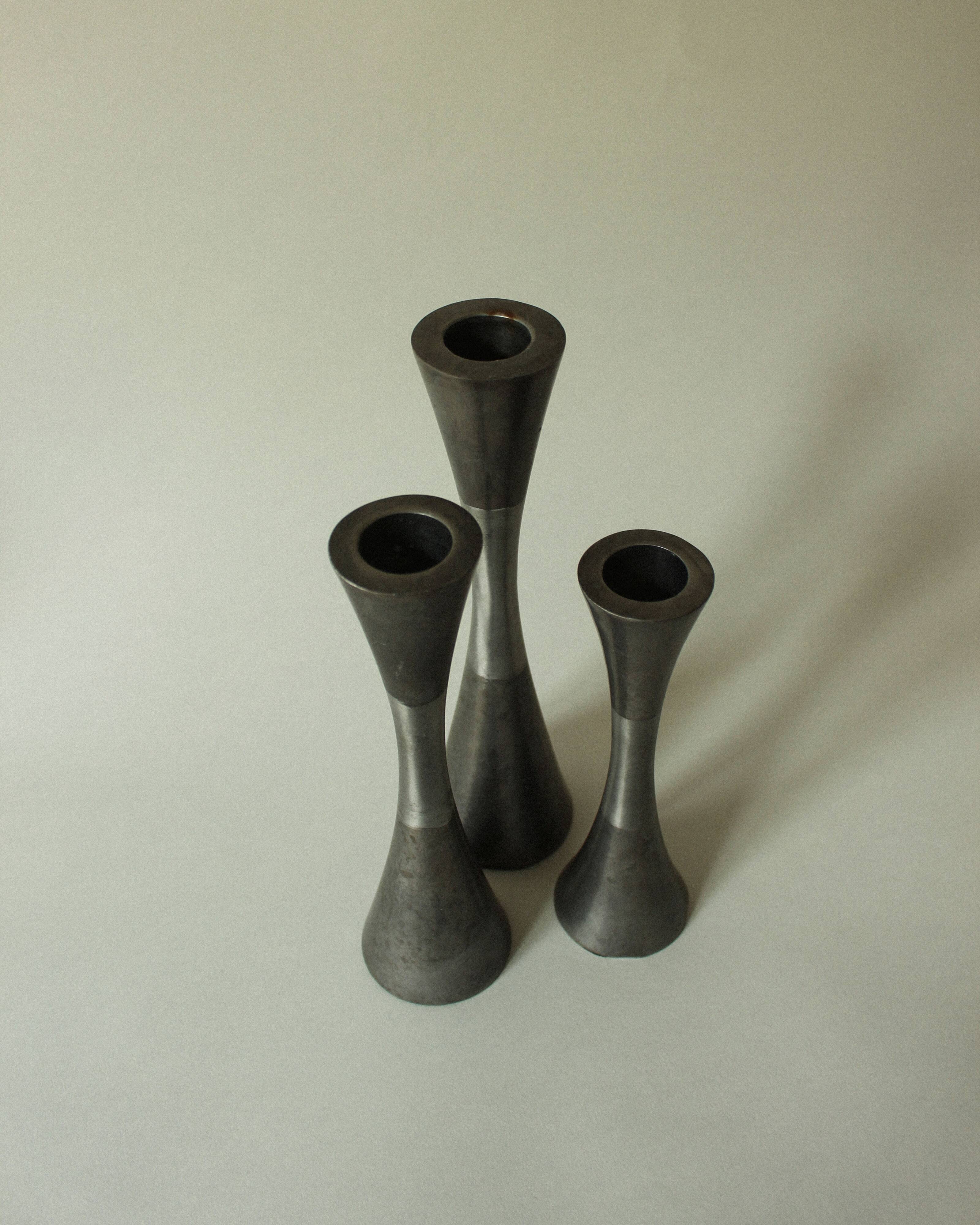Set of three diabolo-shaped candle holders made of cast steel.