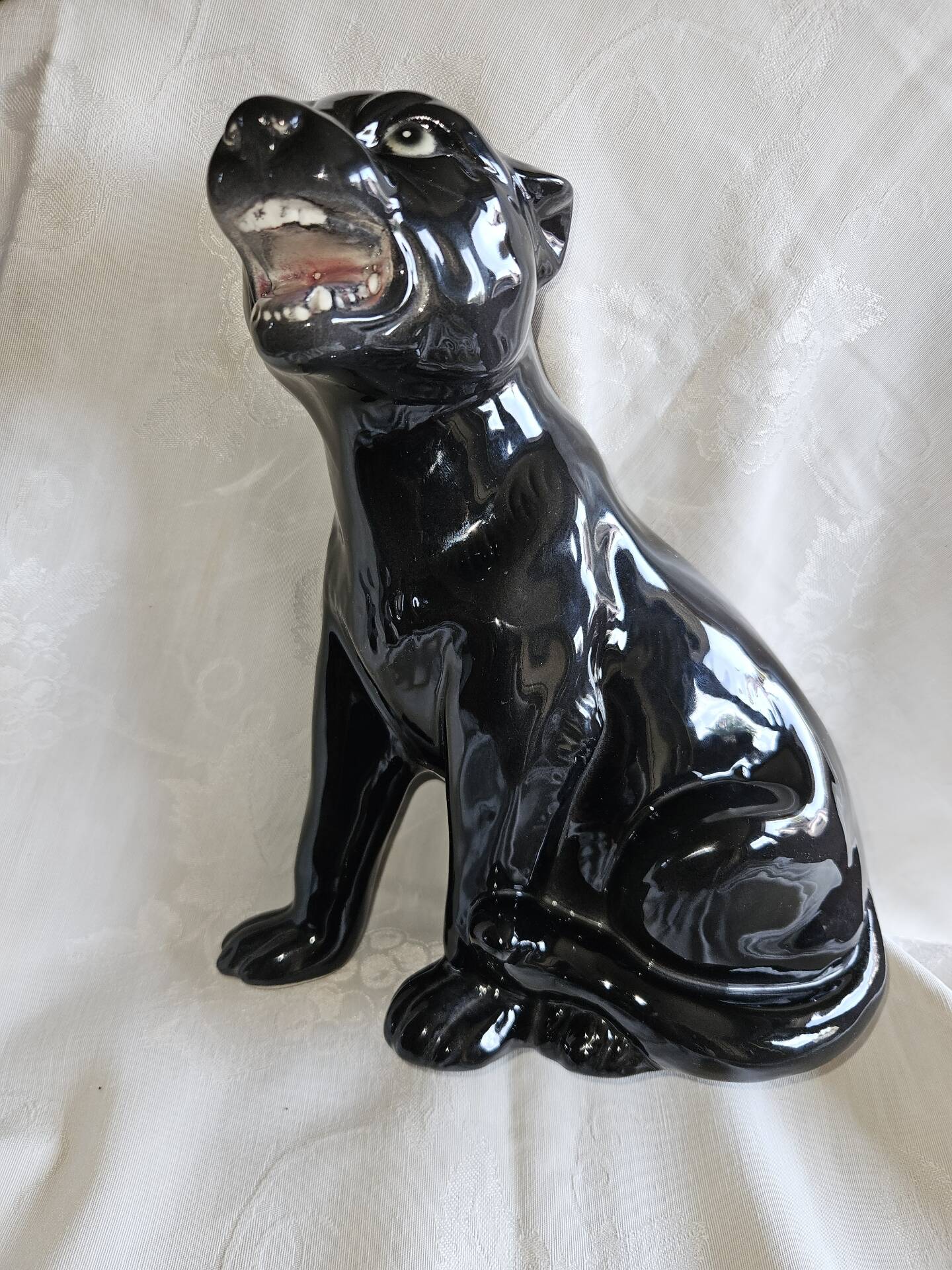 Statue of a roaring panther/leopard sitting in black glazed ceramic.