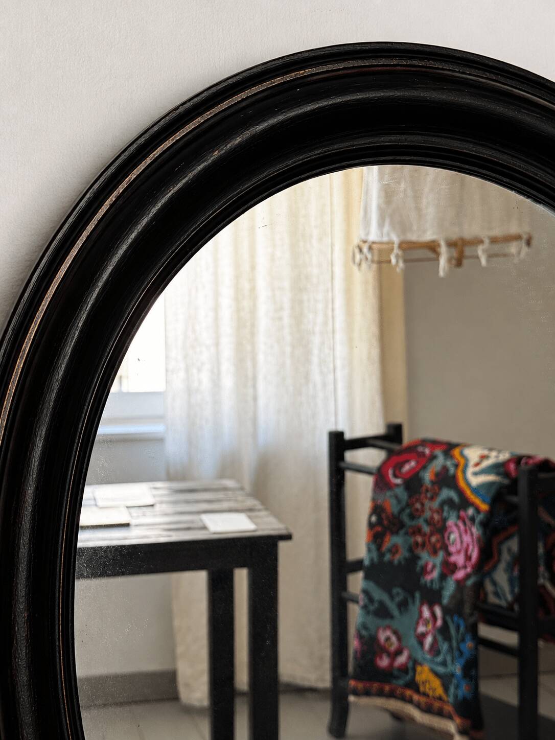 Antique oval mirror in patinated black wood