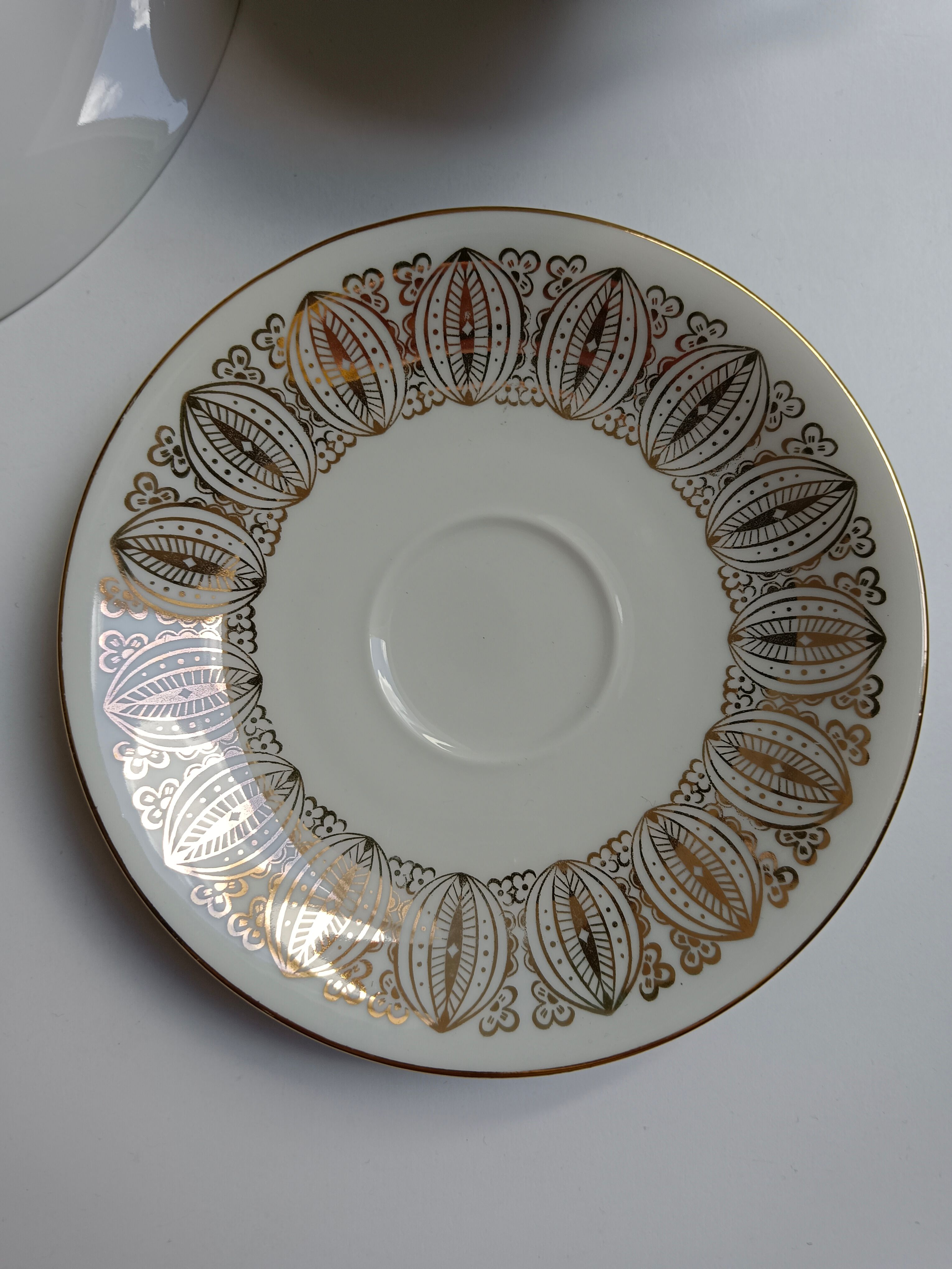 Solitaire tea cup, saucer, and dessert plate in white and gold.