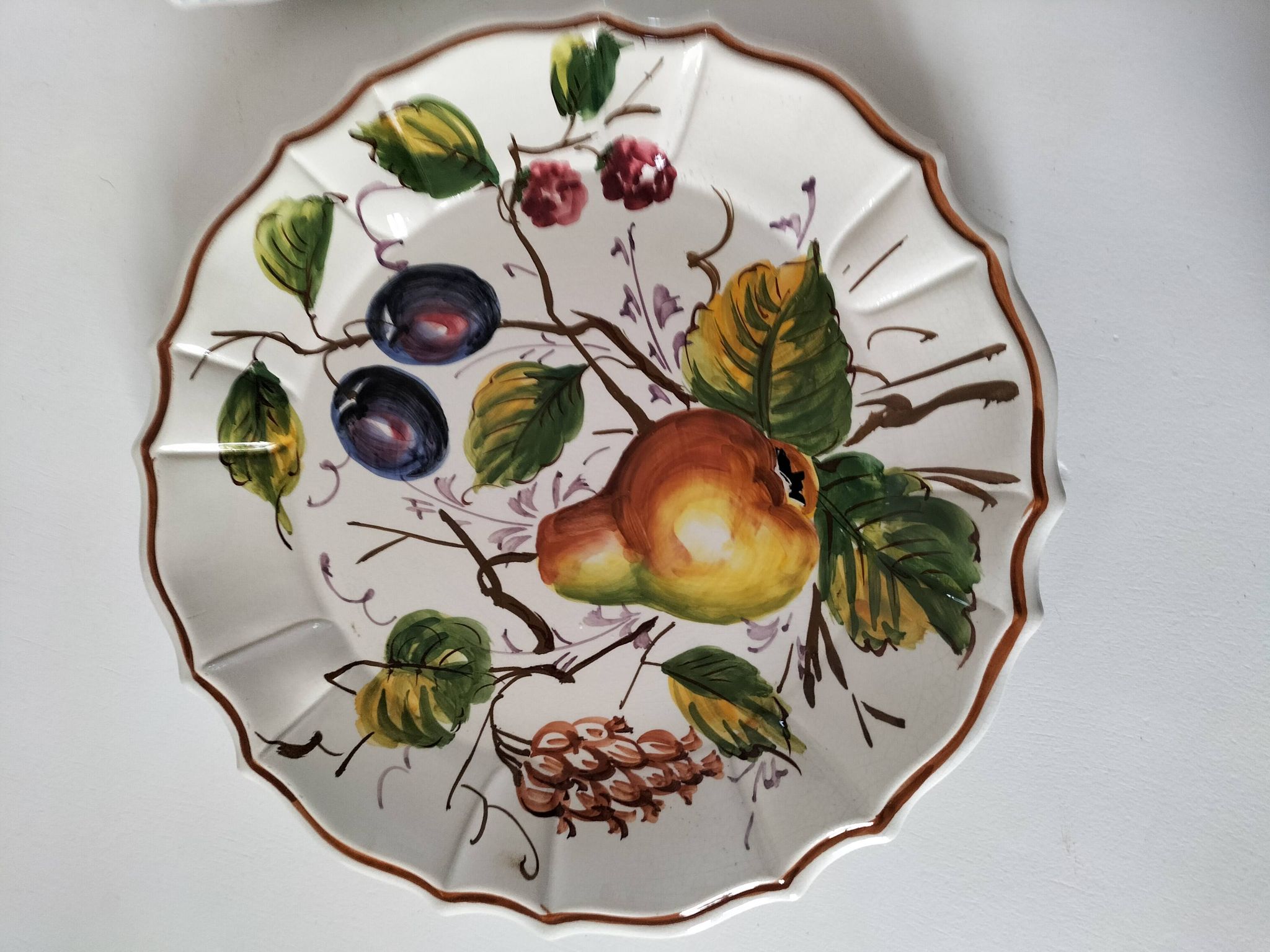 Set of three earthenware plates from Bassano, hand-painted with fruit and flower designs.
