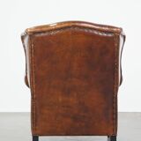 Sheep leather wingback chair with a red corduroy seat cushion and patina
