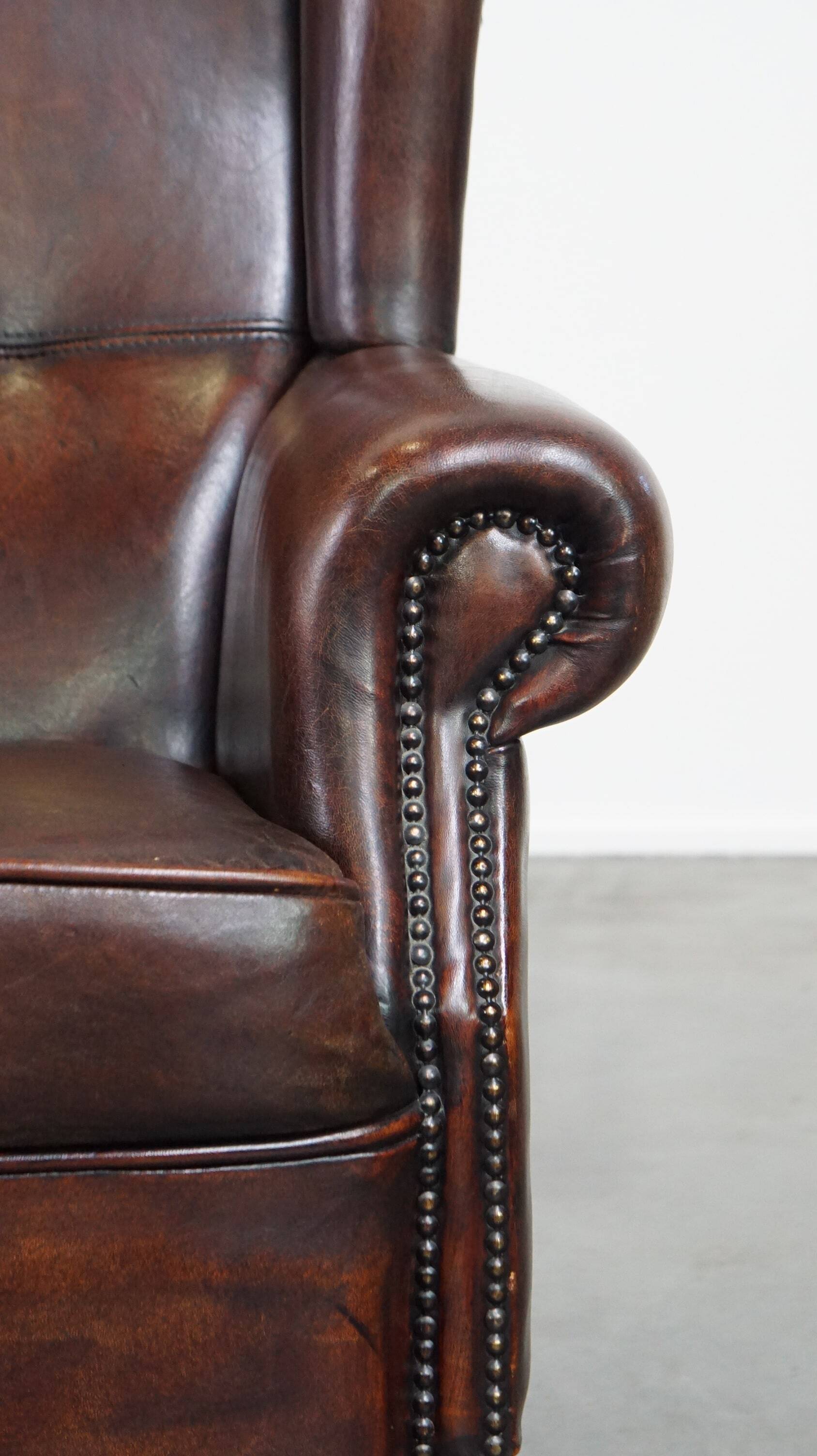 Fauteuil à oreilles confortable et bien entretenu en cuir de mouton