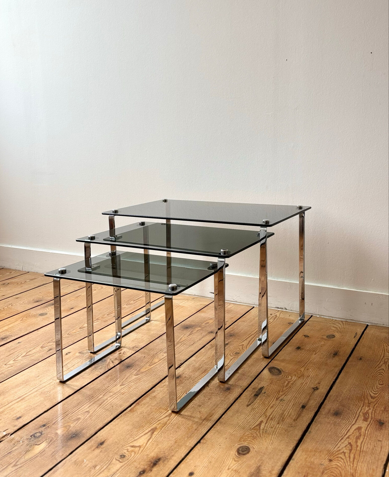 Nest of coffee tables in chrome with smoked glass top.