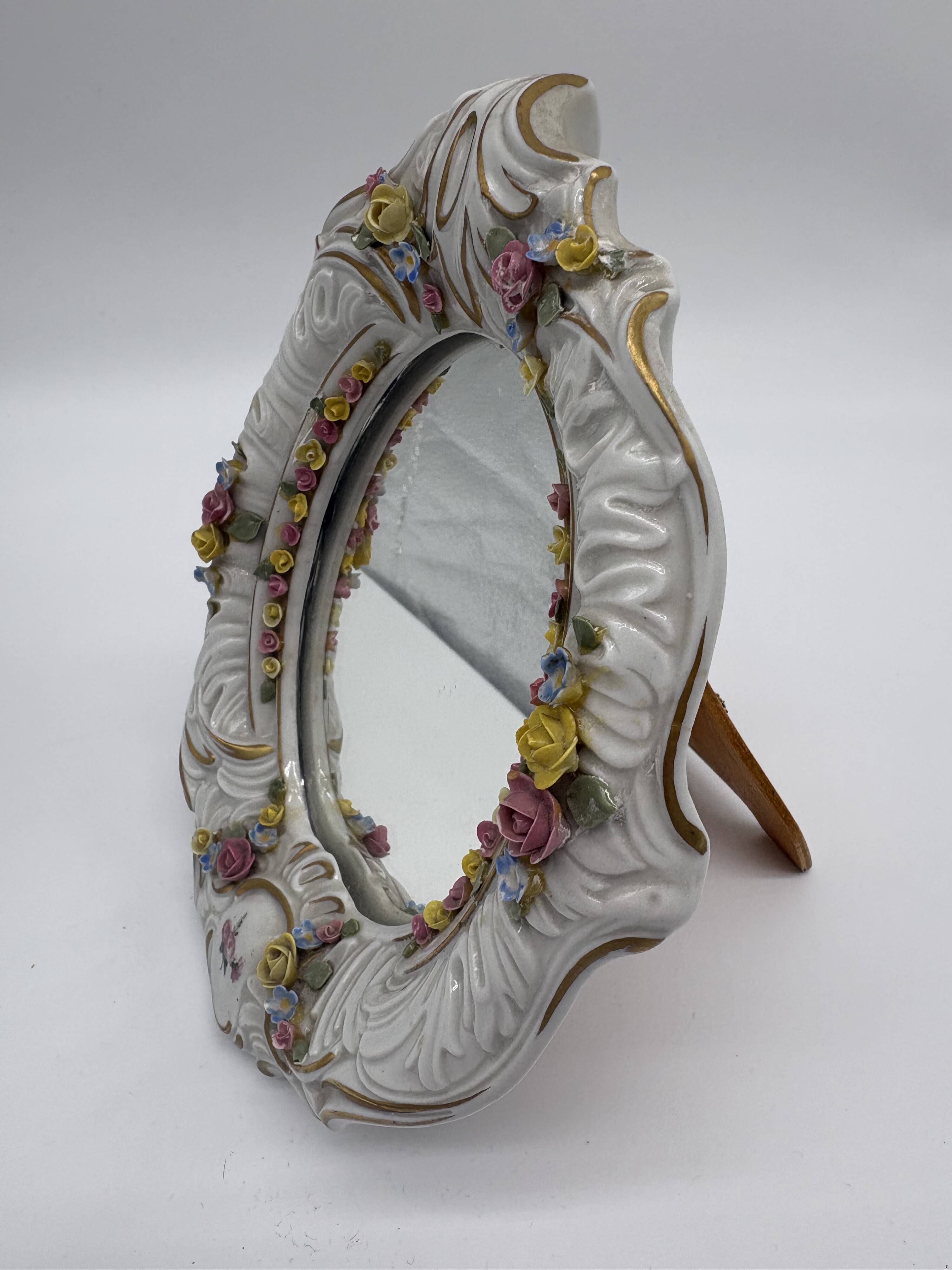 Antique porcelain mirror from Dresden with relief flowers and rococo decoration.