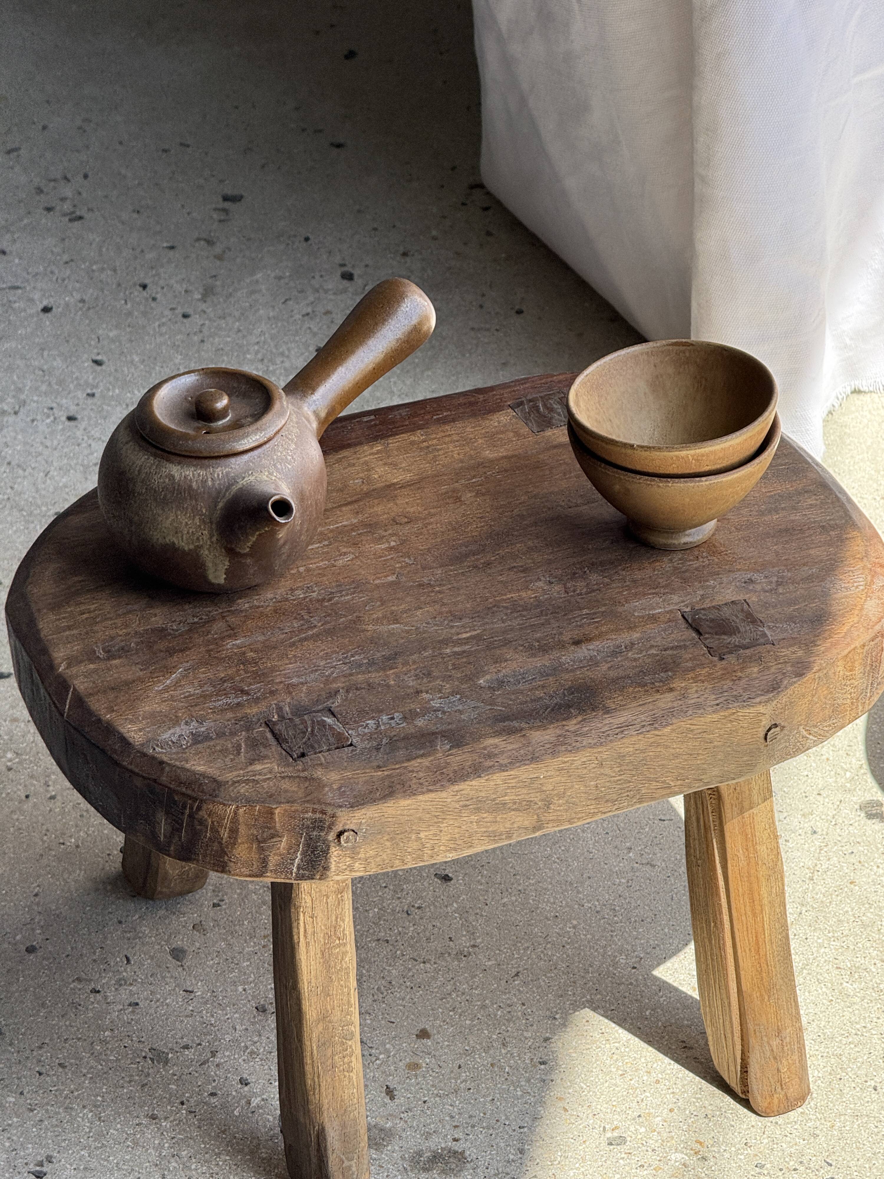 Small stool, oval solid teak side table with curved legs in wabi-sabi style.