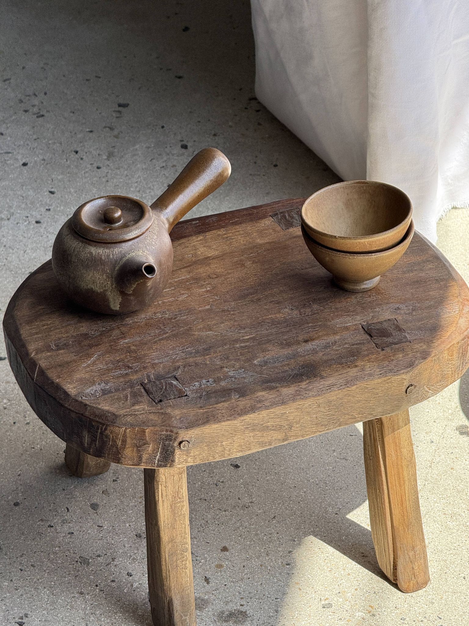 Small stool, oval solid teak side table with curved legs in wabi-sabi style.