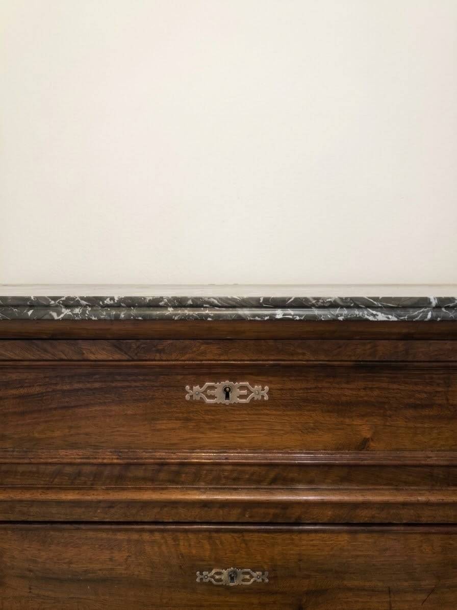 Antique wooden chest of drawers with a marble top.
