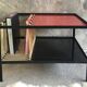 Modernist metal coffee table with a magazine rack in 1950s design.