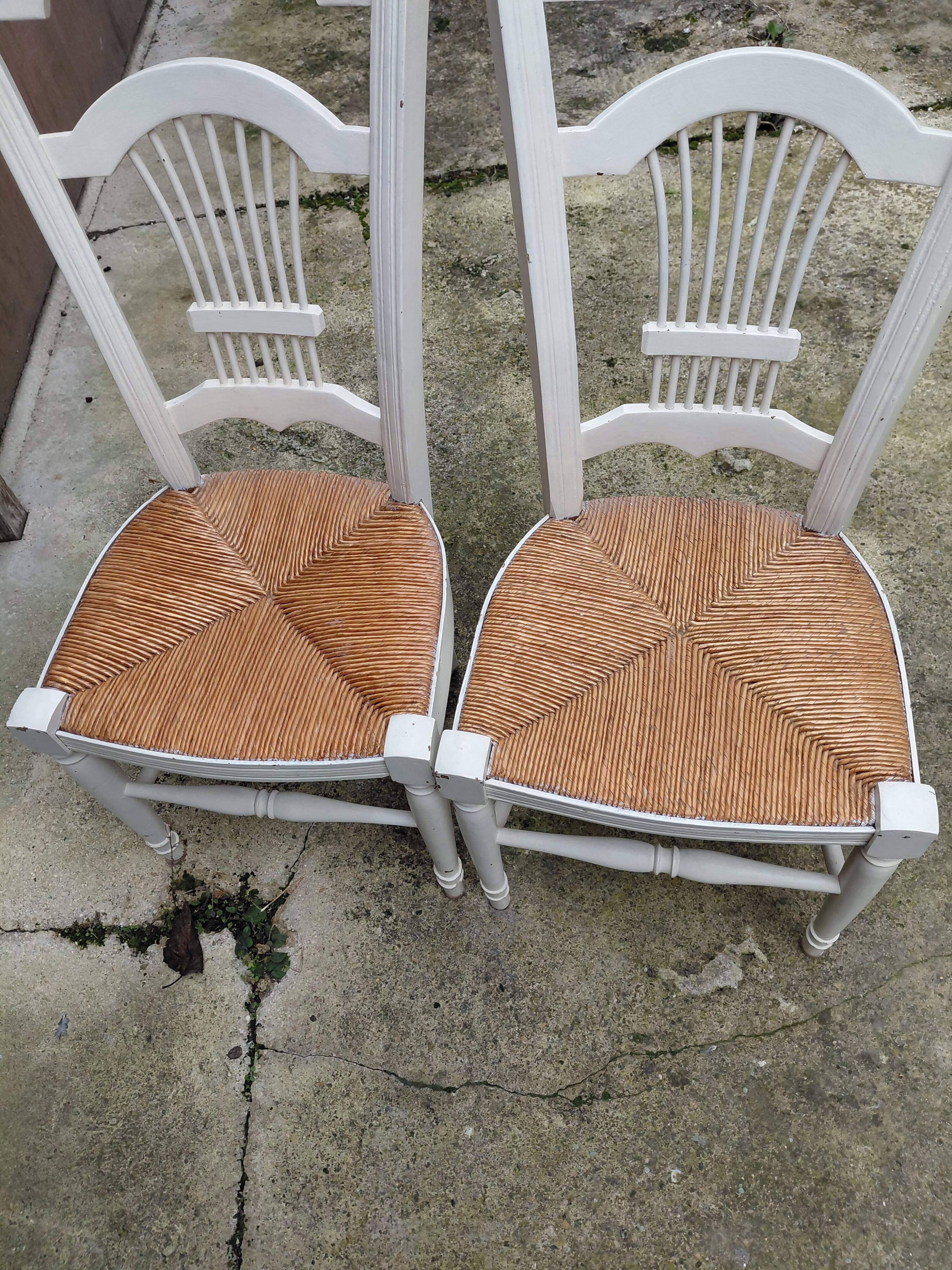 Pair of straw-seated chairs with white-stained wood.