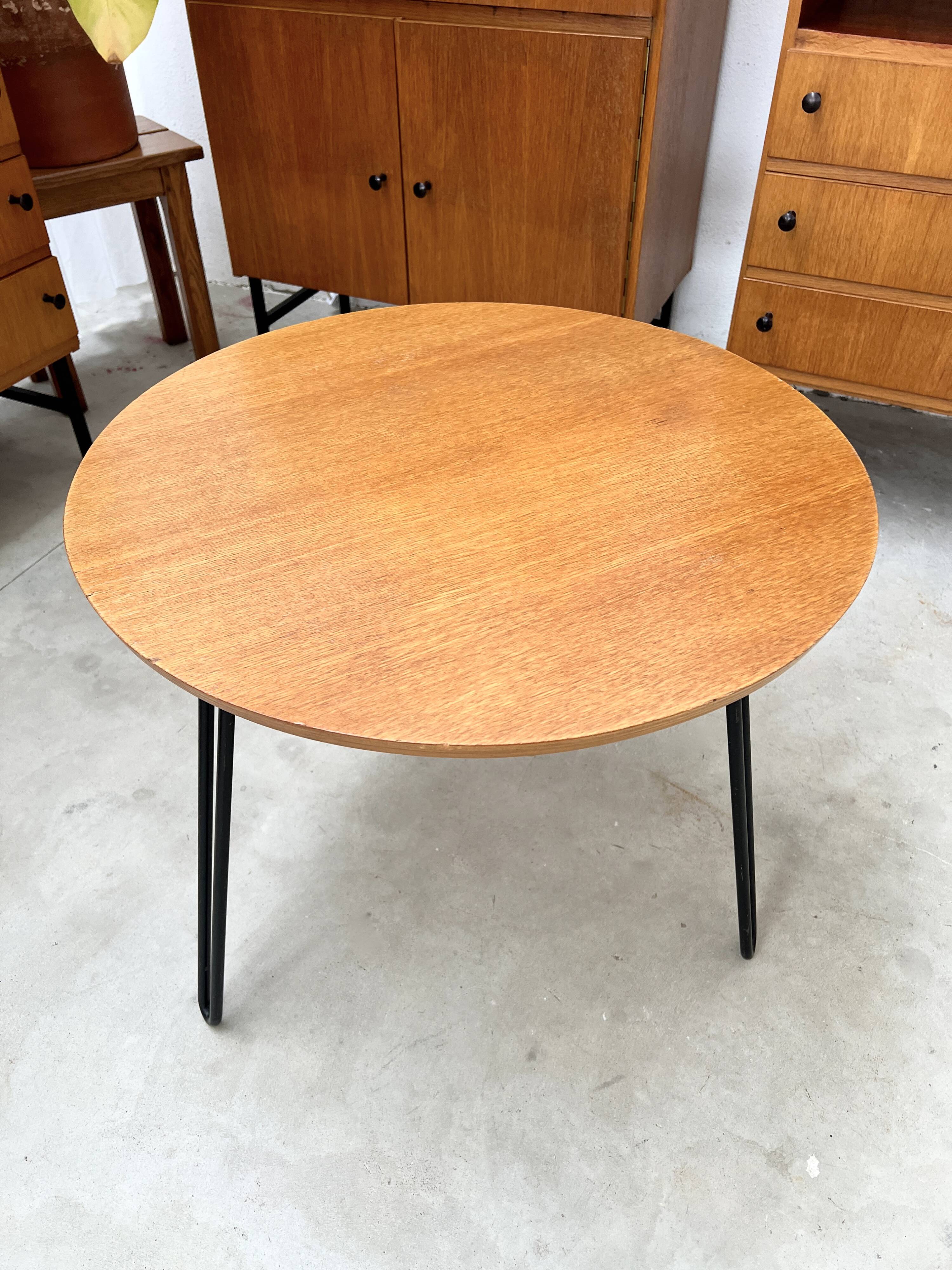 Round side table with black lacquered metal hairpin legs.
