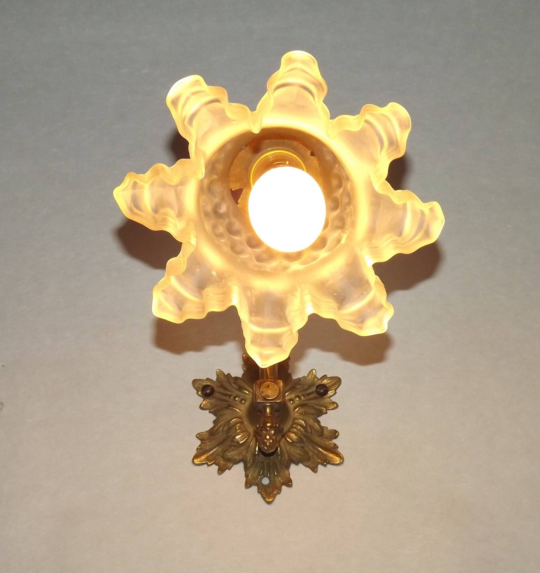 Simple wall sconce in French Art Nouveau bronze with a white glass shade featuring patterns.