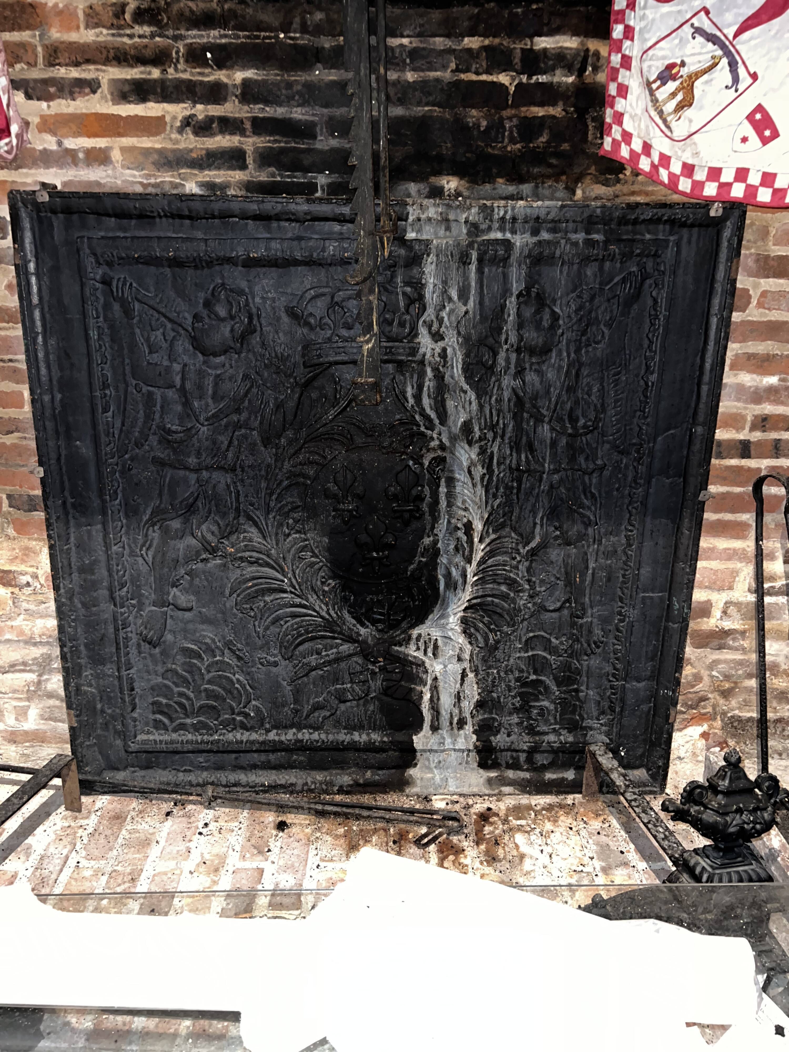 huge old fireplace plate has decoration of angels, crown and fleurs-de-lis