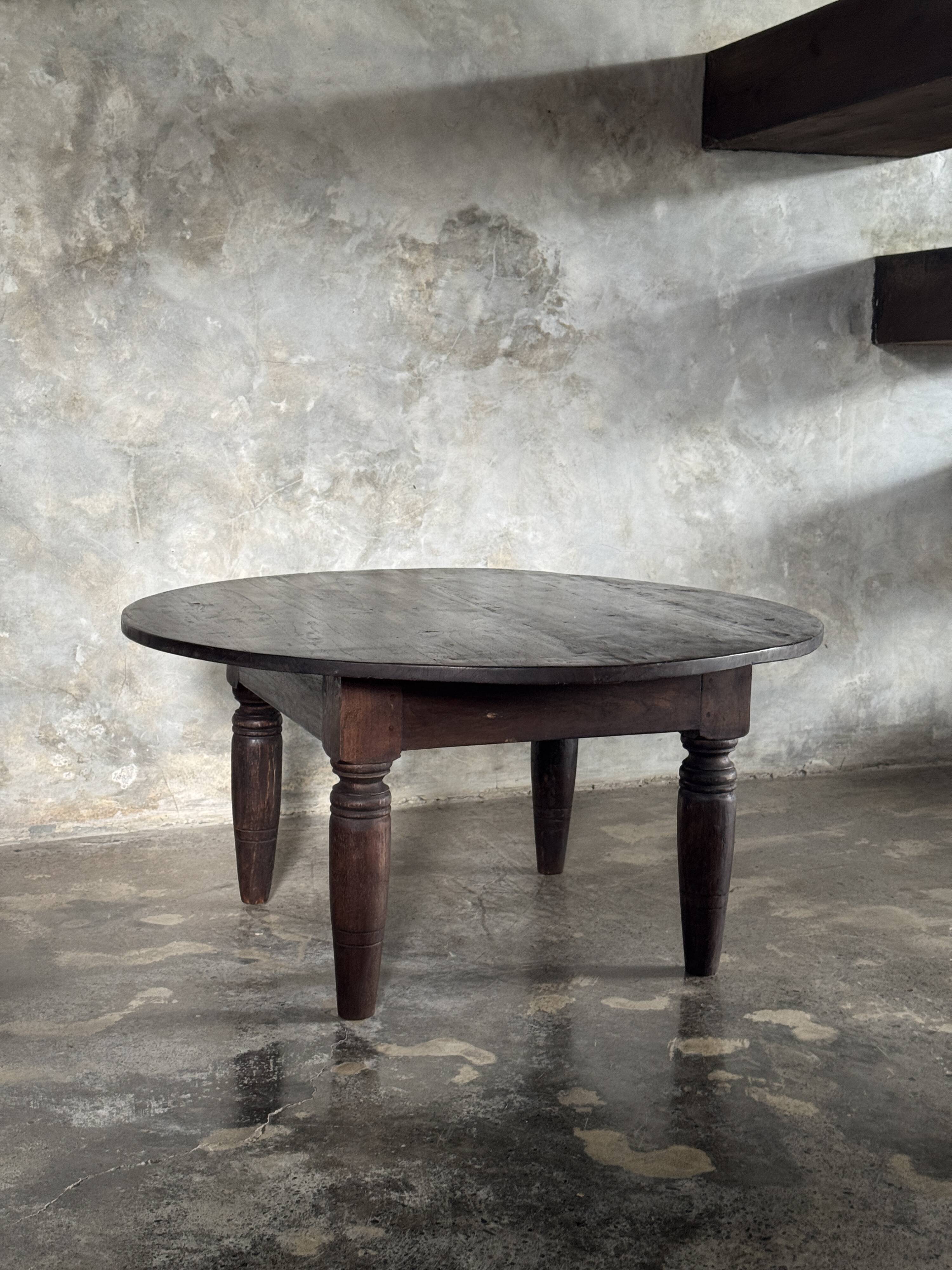 Antique round coffee table in Indonesian teak with turned legs.