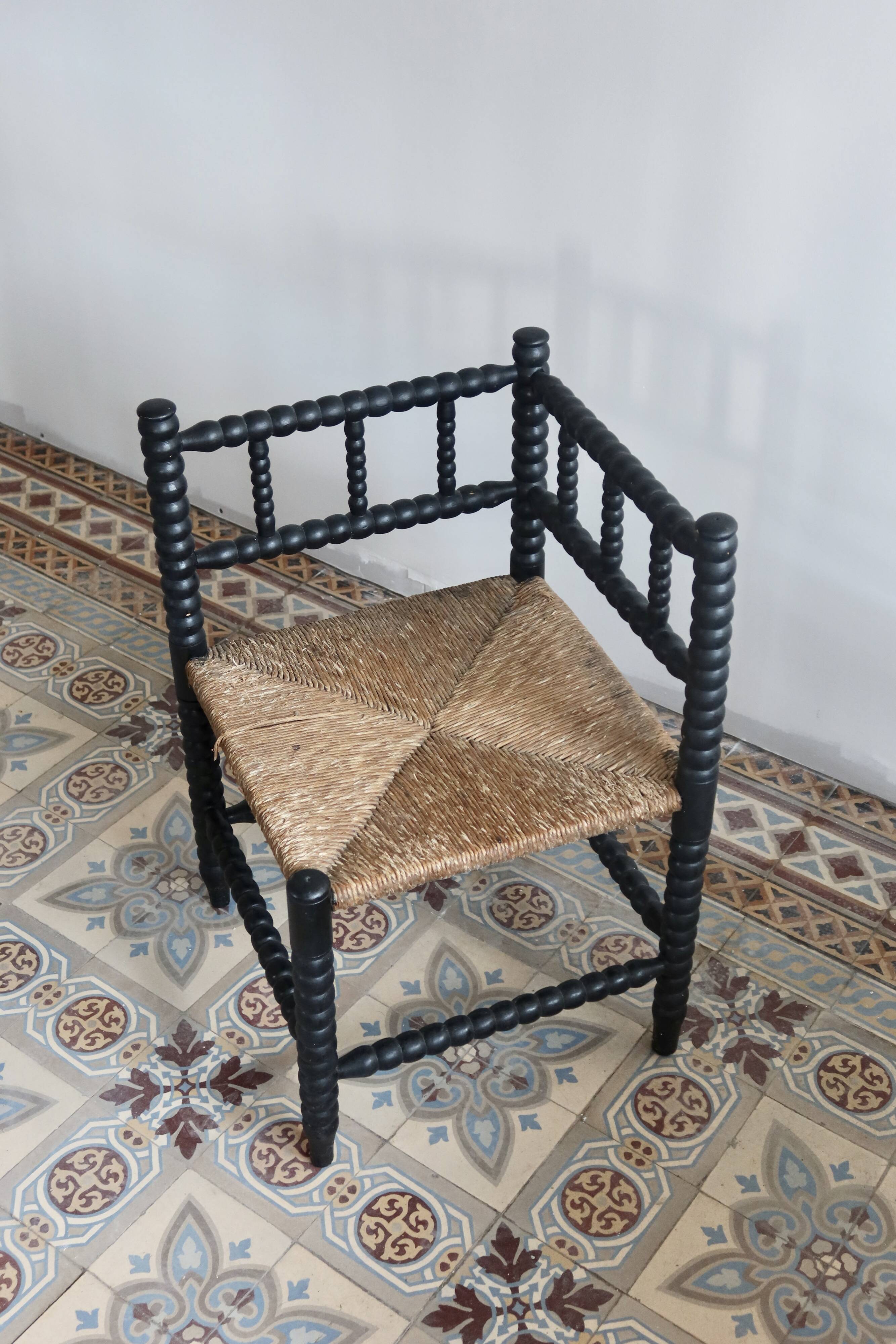Antique black turned wood corner chair with a straw seat.