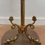 A round, neoclassical-style brass side table with a base decorated with dolphins and a red celluloid top encircled by an openwork gallery, attributed to the House of Jansen.