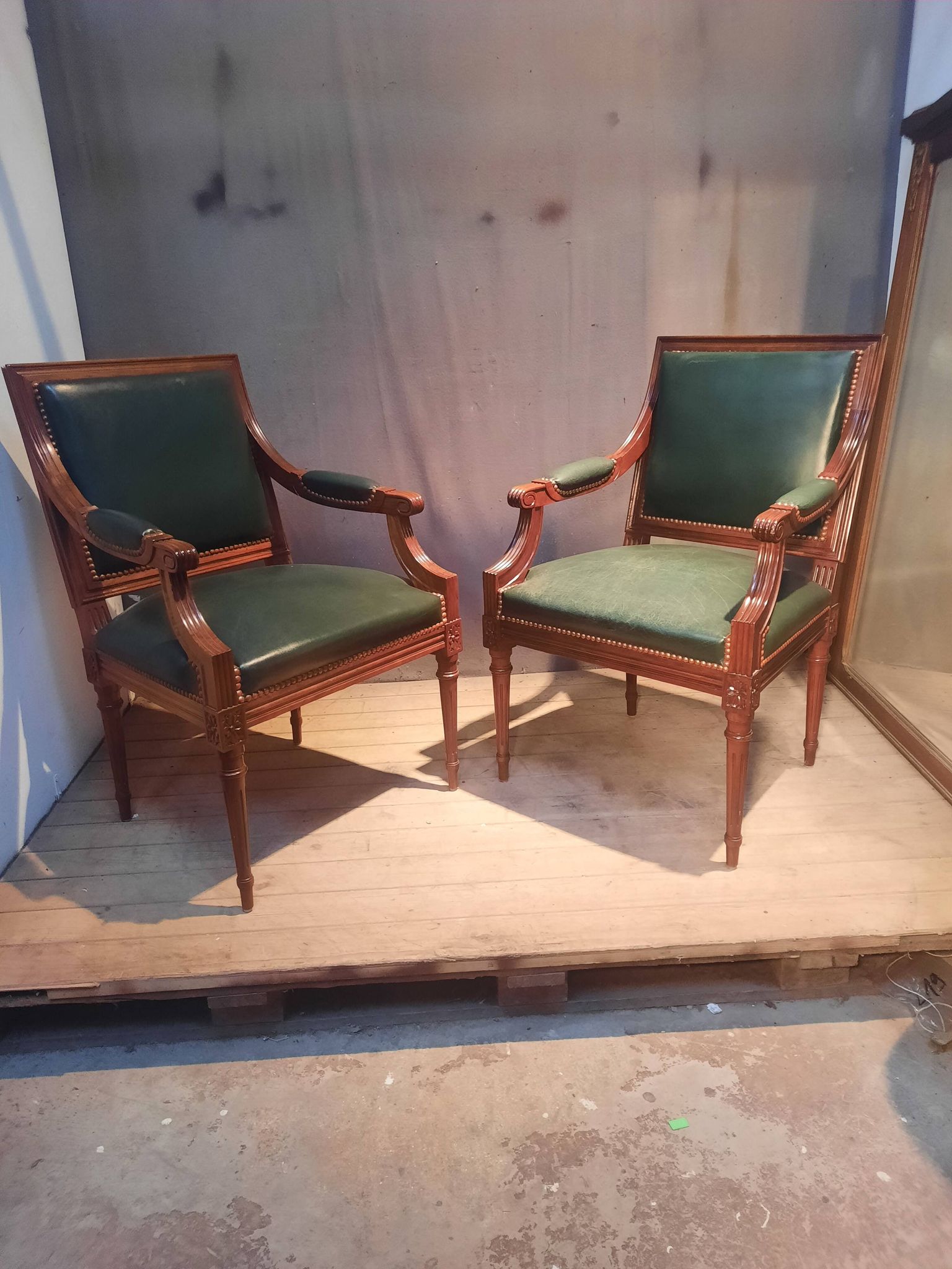 Pair of Louis XVI style armchairs upholstered in green leather.