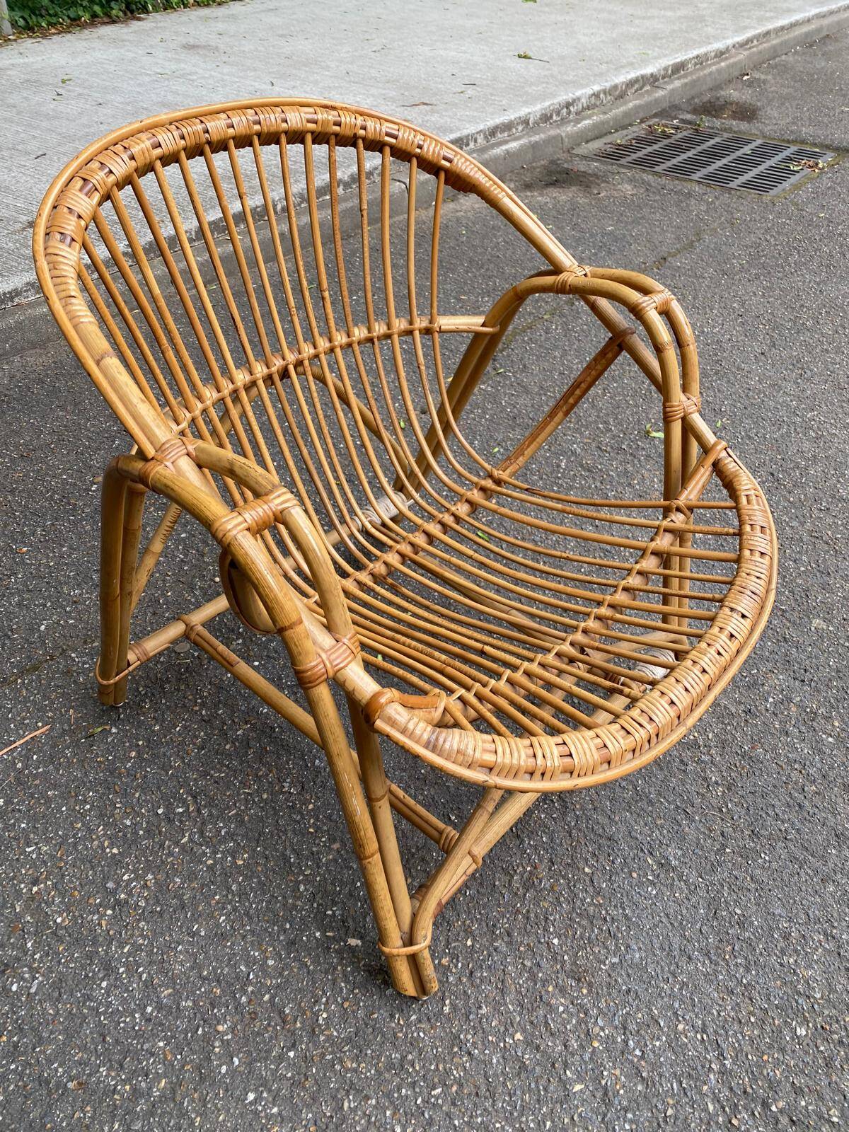 1970s adult rattan and wicker armchair with a round burgundy velvet cushion.
