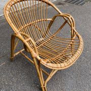 1970s adult rattan and wicker armchair with a round burgundy velvet cushion.