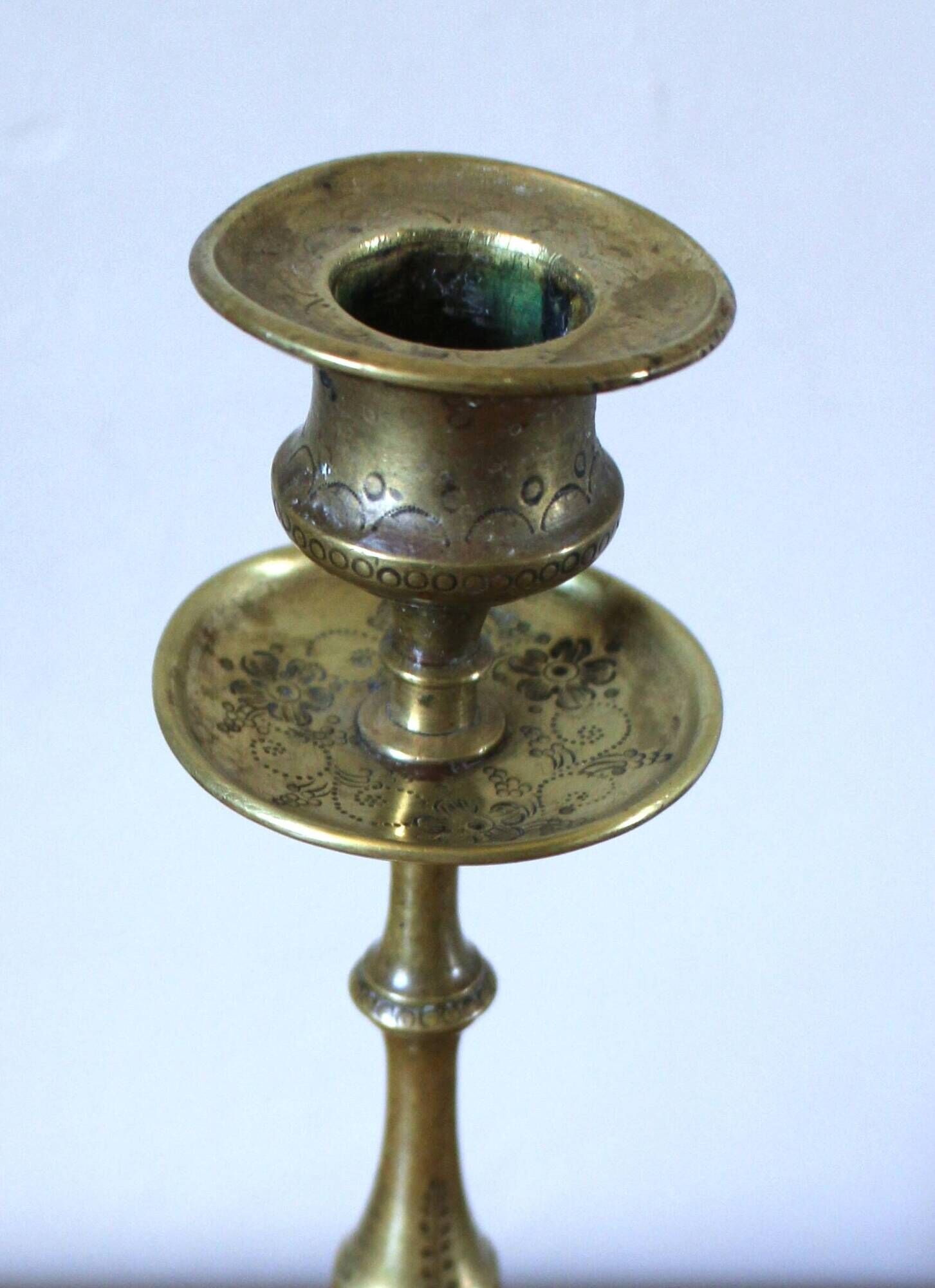 Brass candle holder with flowers and round shape.