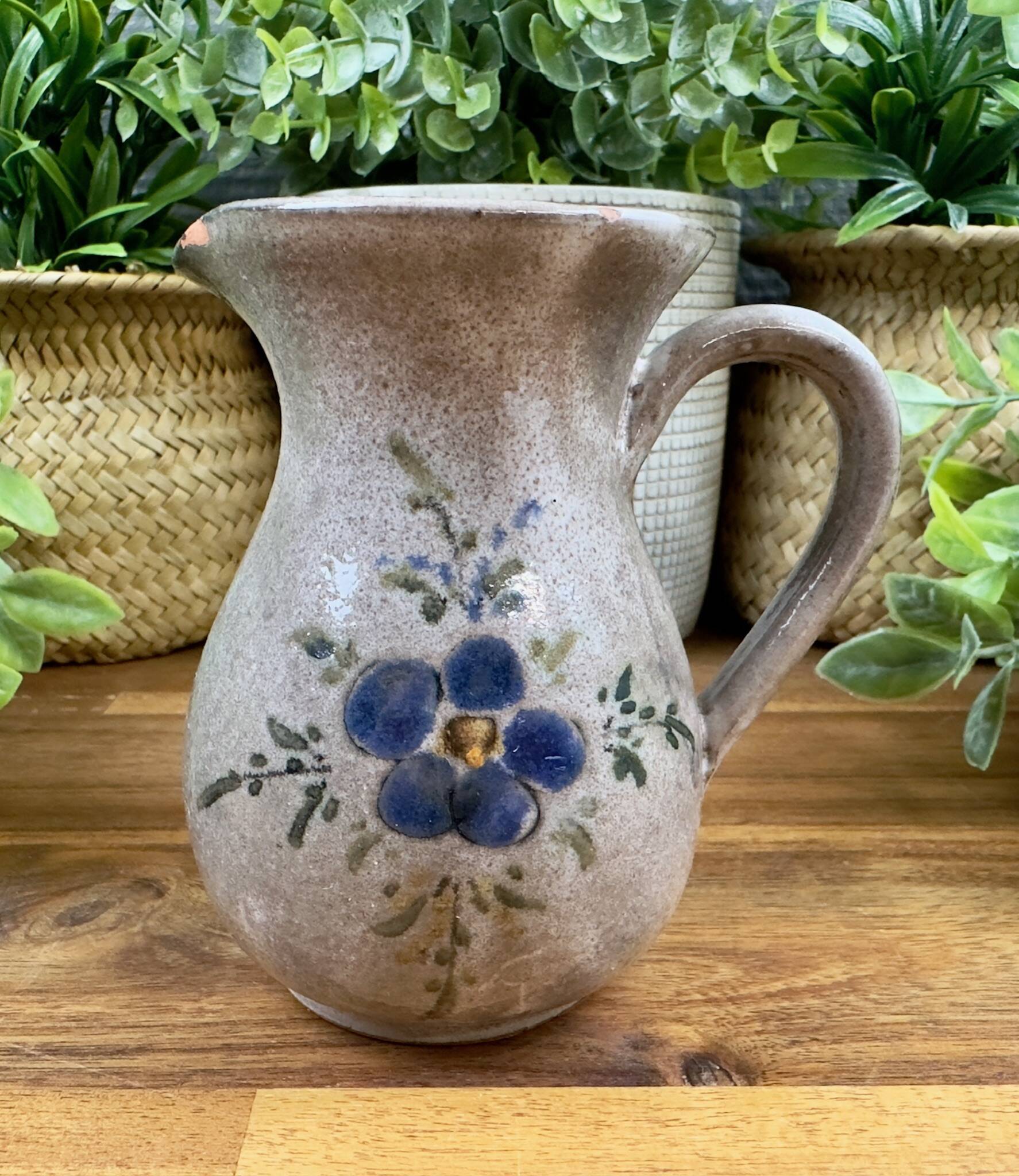 Vintage grey ceramic pitcher with hand-painted blue flower decoration.