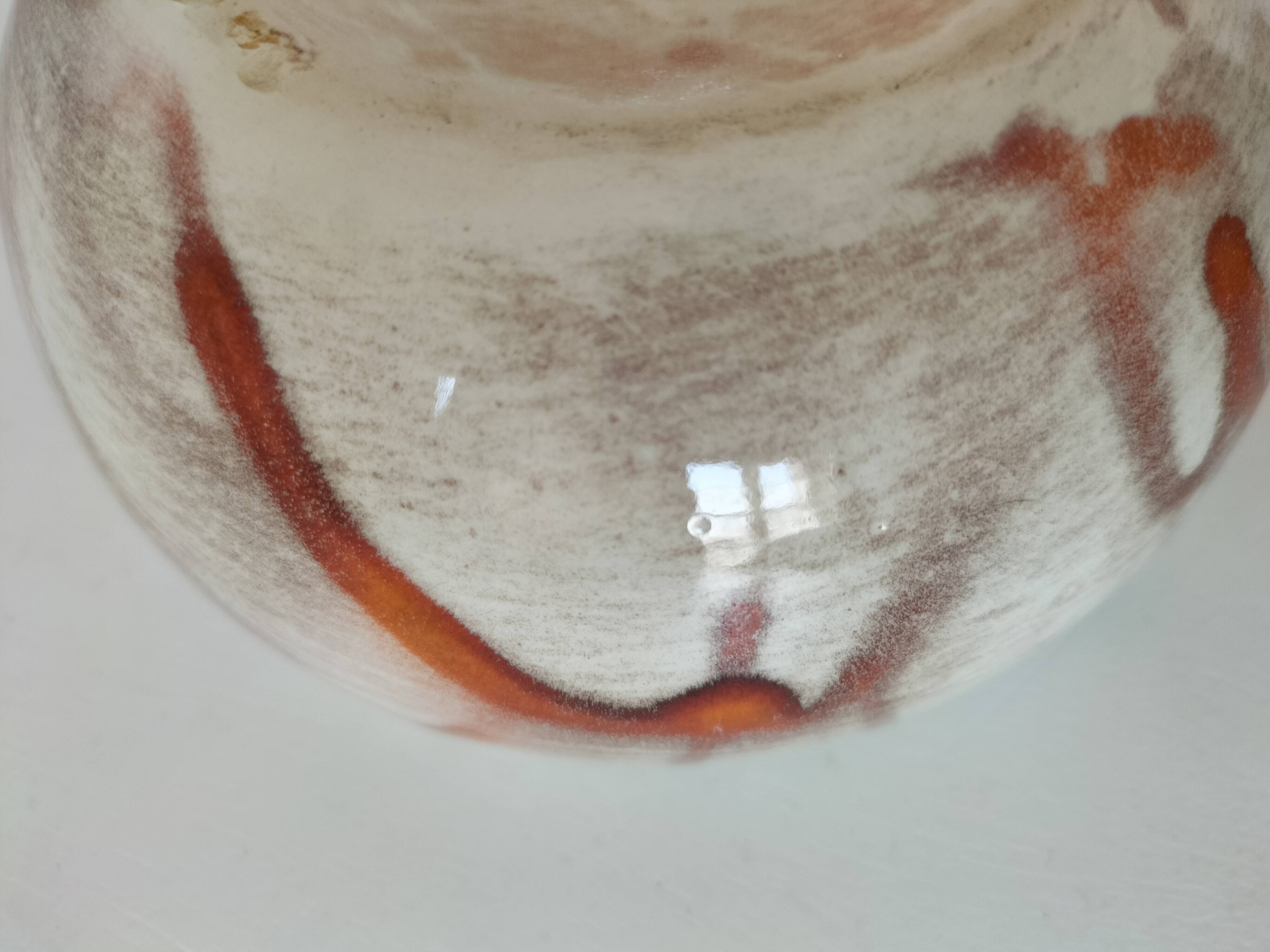 Red-orange glazed ceramic workshop bowl with floral decoration.