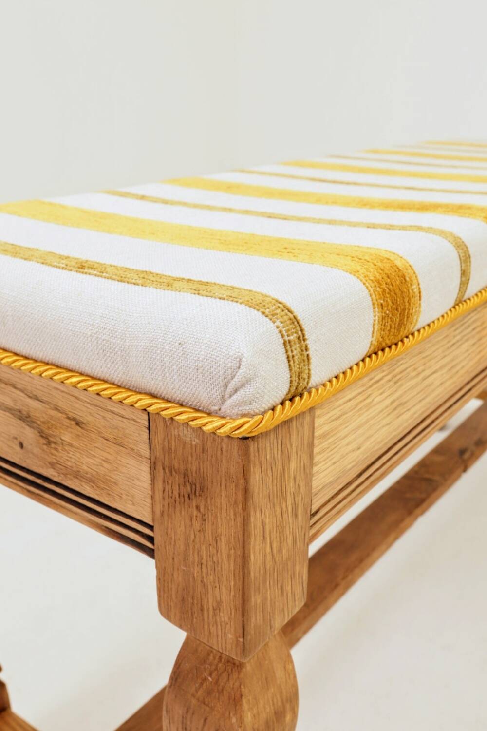 Vintage oak bench with striped linen fabric in a country style.