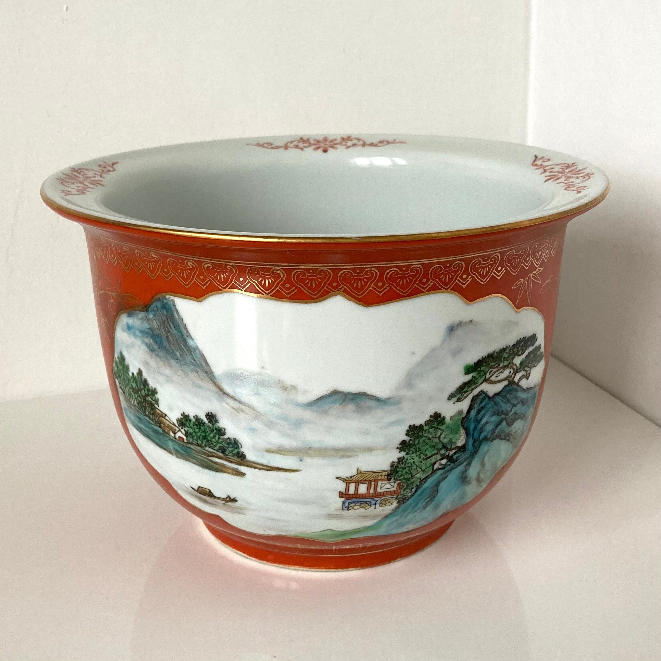 Chinese planter or Chinese porcelain pot cover decorated with landscapes on a coral and golden background