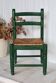 Vintage children's chair in green wood with a woven straw seat