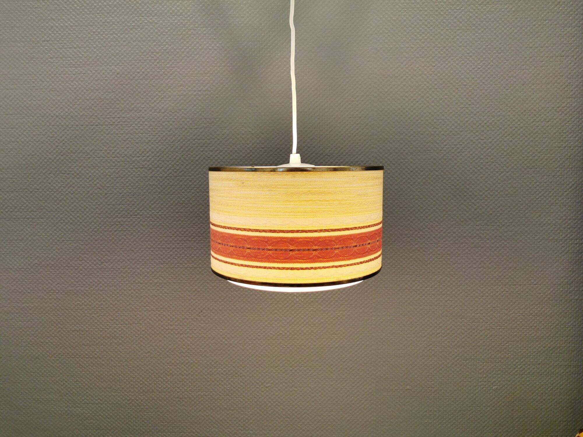 Hanging lamp with brass-coloured details, made of fabric with intact plastic bottom grille.