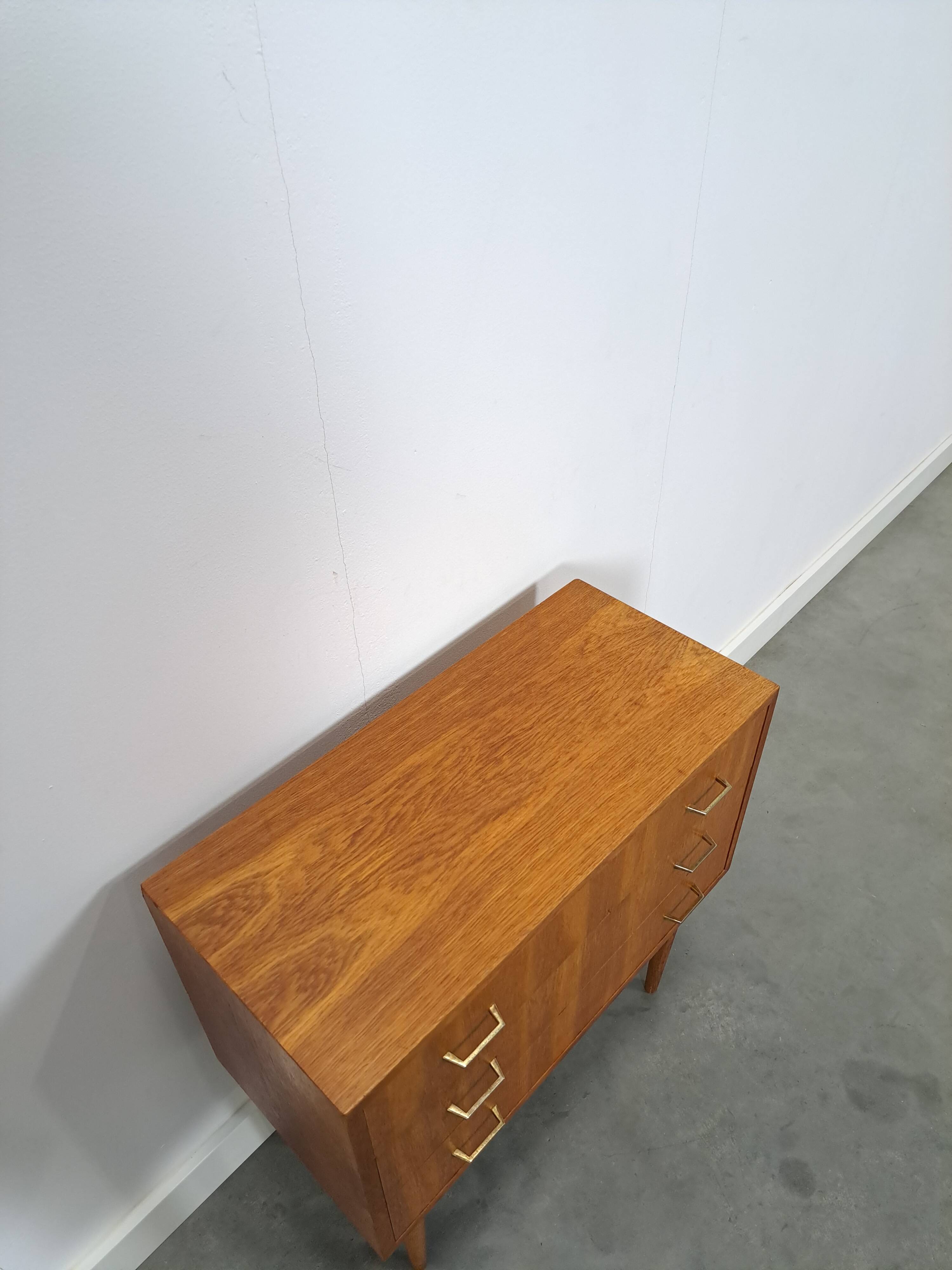 Commode danoise avec de hauts pieds et des poignées dorées.