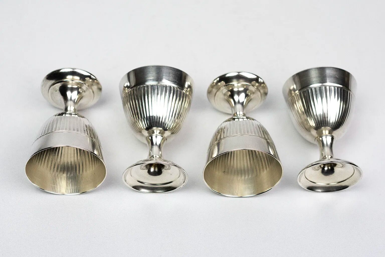 Four silver-plated Christofle egg cups with fluted sides.