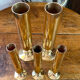 Set of candlesticks and tubular vases in solid brass.