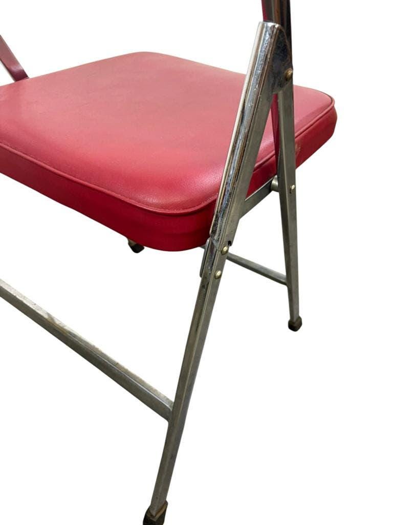 Vintage folding chair in red faux leather with a chrome frame.