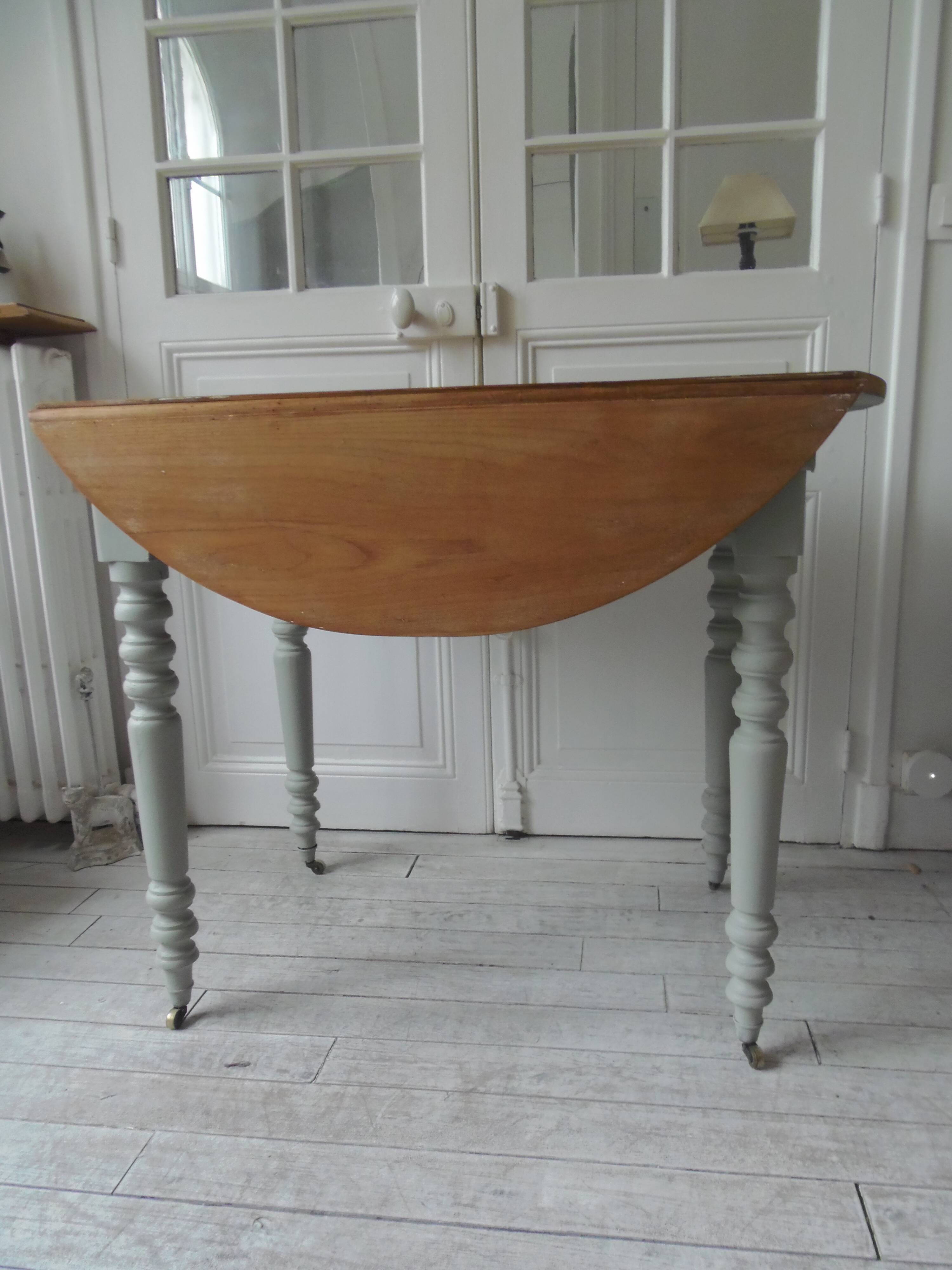 Walnut table with raised flaps, base on verdigris casters.