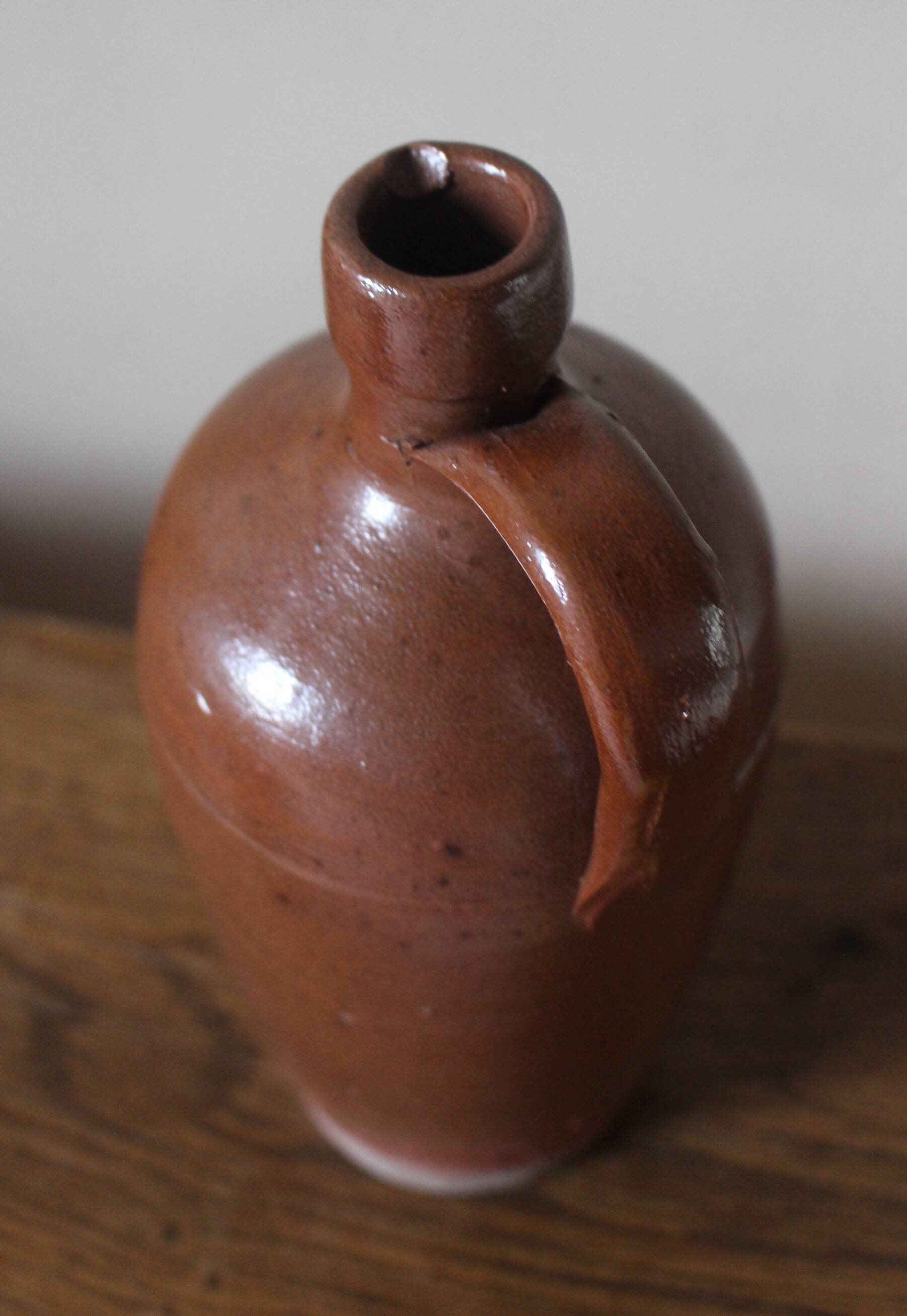 Vintage stoneware liqueur bottle with handle and spout.