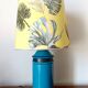 Blue ceramic lamp with claw feet and foliage lampshade.
