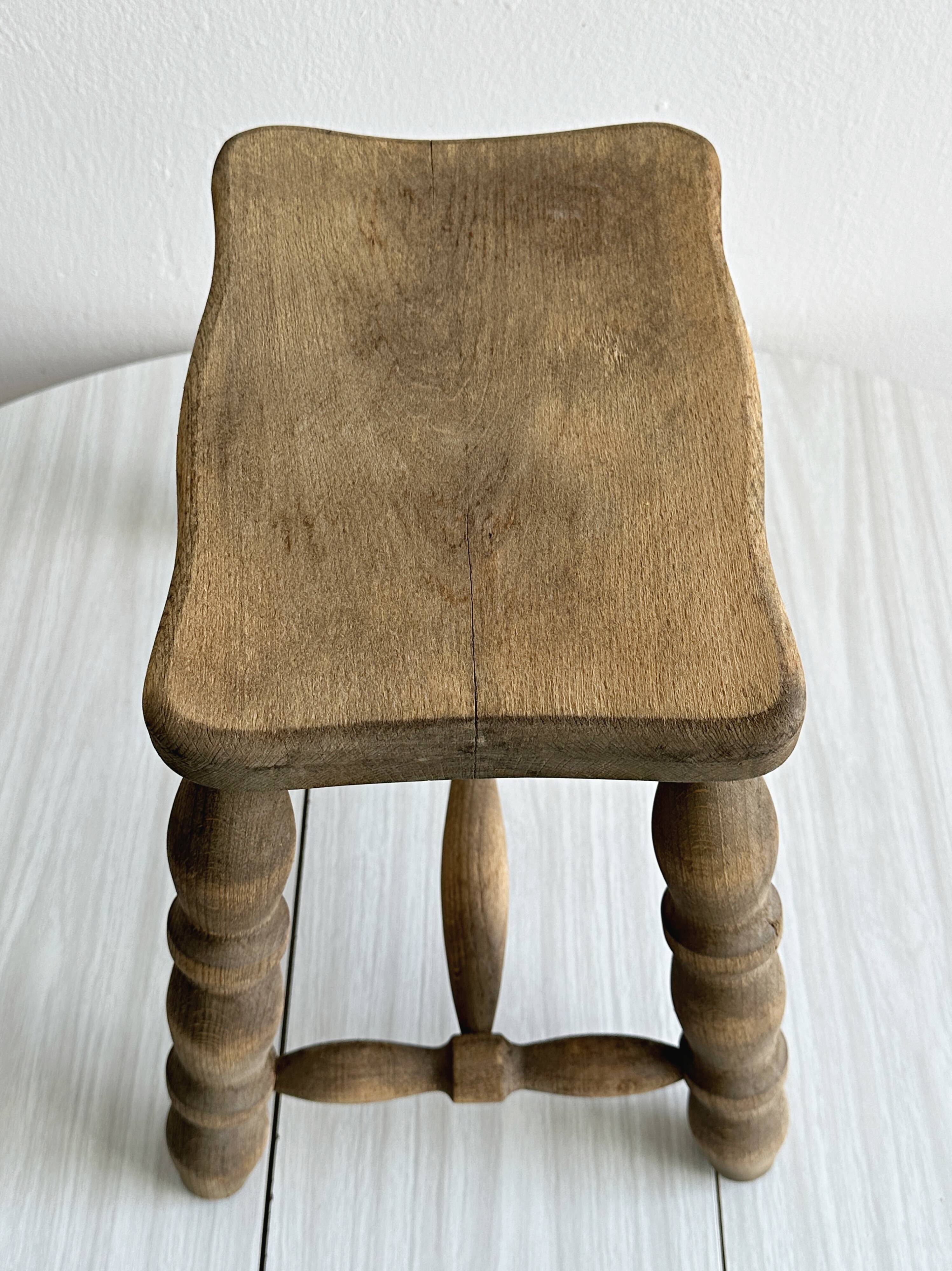 Antique wooden stool with four turned legs.