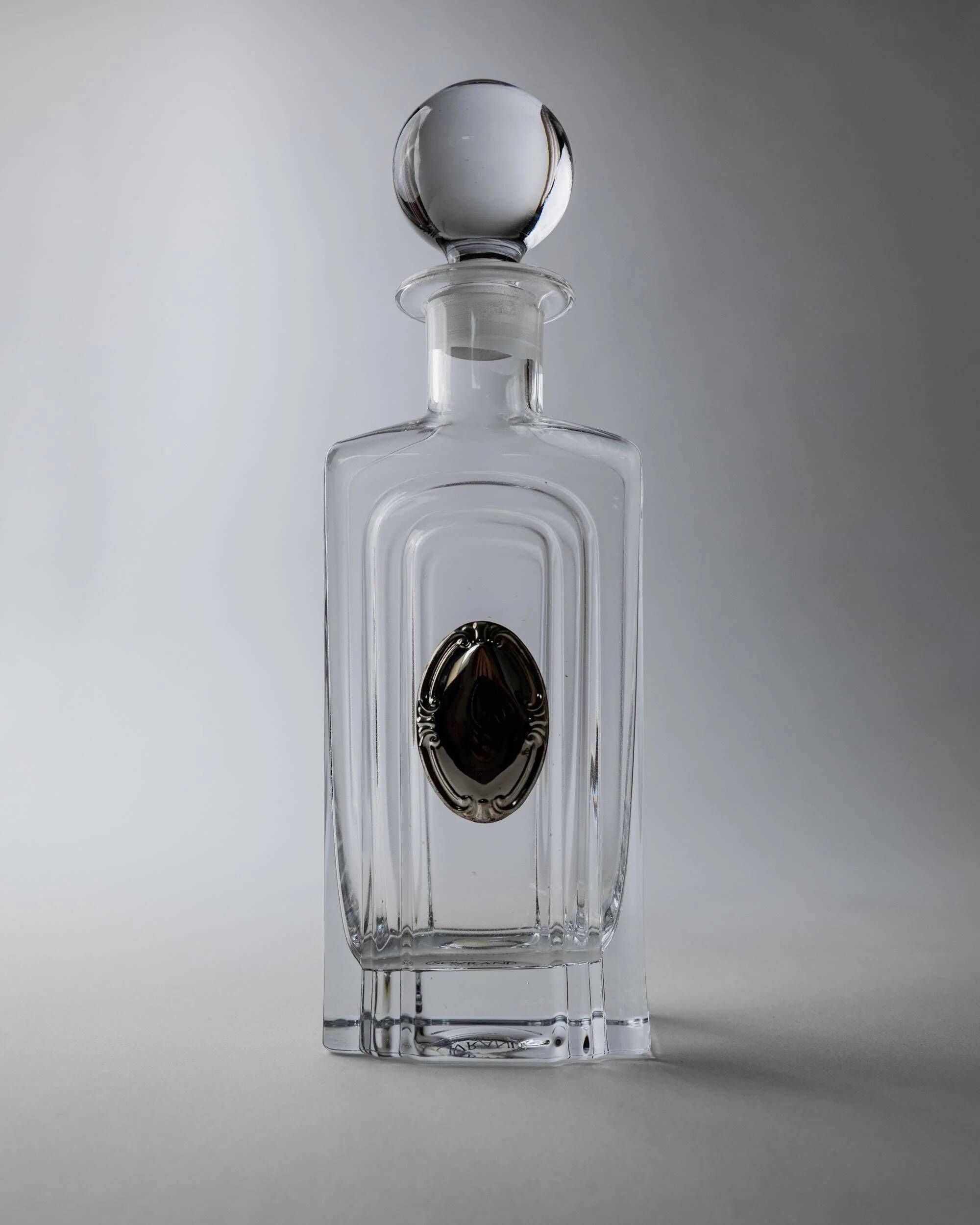 Vintage glass decanter from the 1980s, transparent glass with a silver plate and spherical stopper.