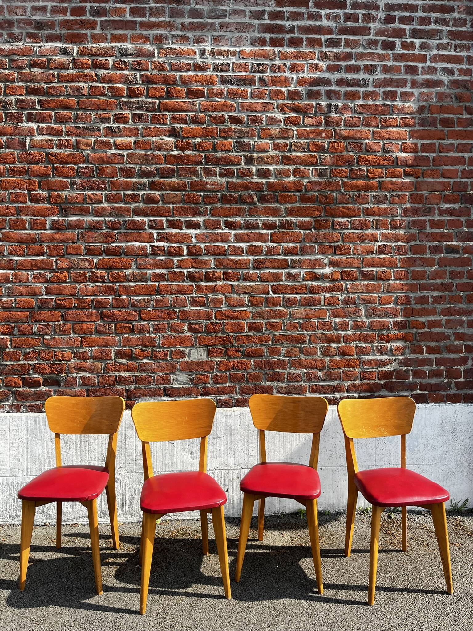Set of 4 vintage bistro chairs in wood and red faux leather, with splayed legs.