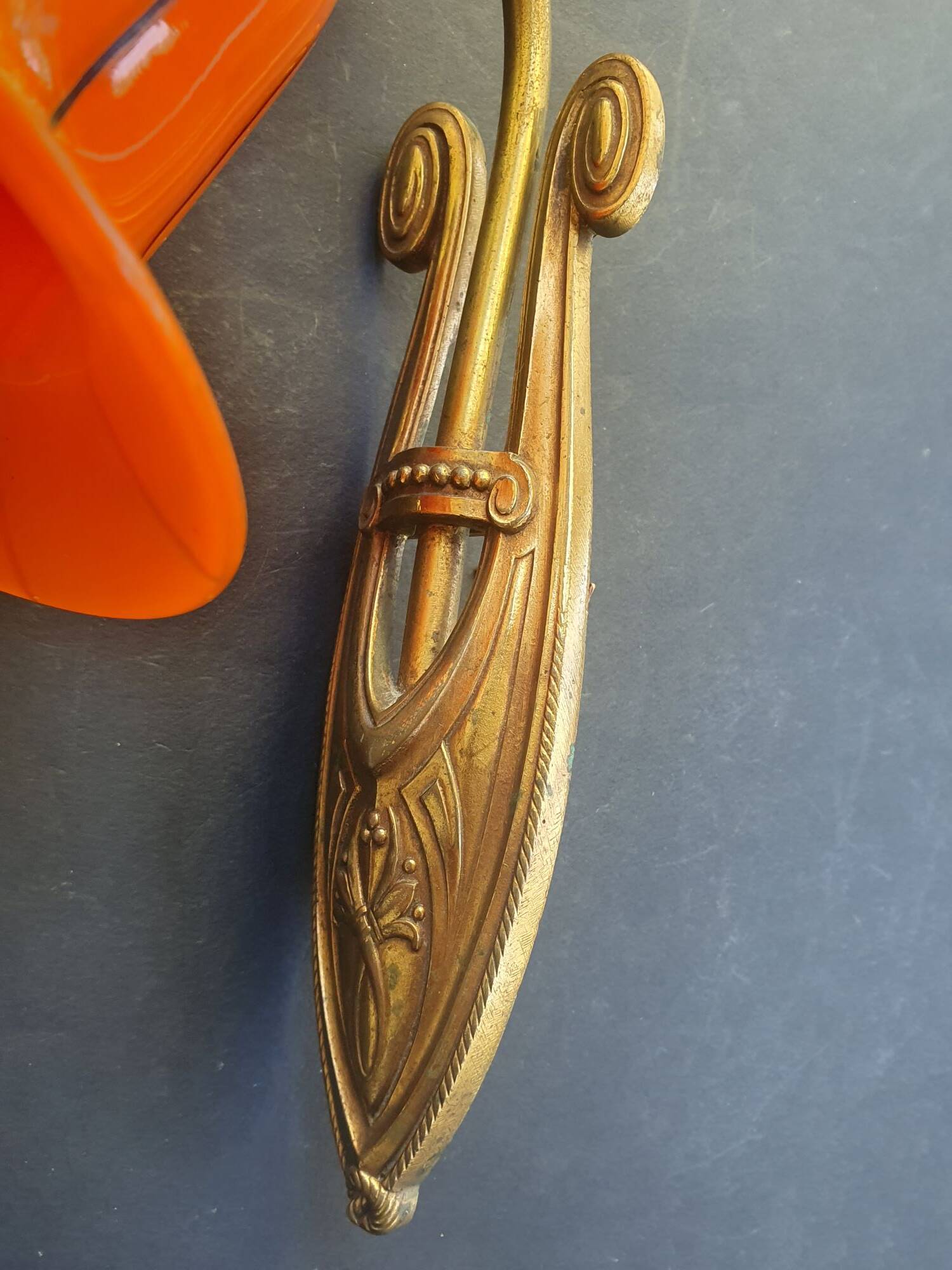 Art Deco wall light in brass with an orange globe.